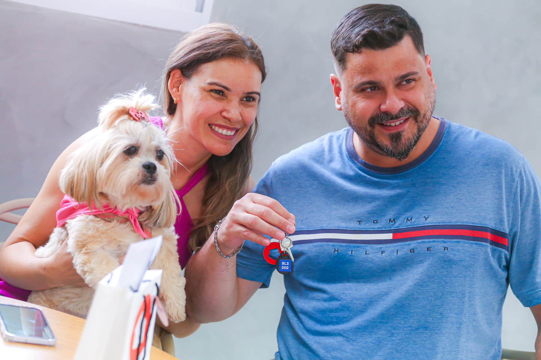 Casal com seu cachorro mostra as chaves do novo apartamento